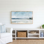 Snowy landscape Frame TV art above a white console with a rattan basket in a coastal living room
