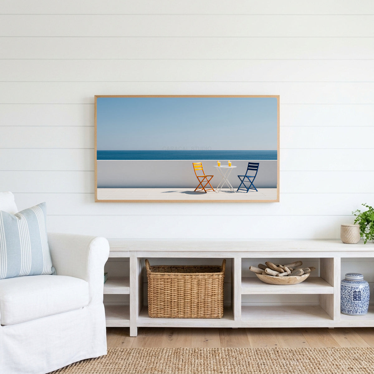 Ocean view terrace Frame TV art above a white console with a rattan basket in a coastal living room