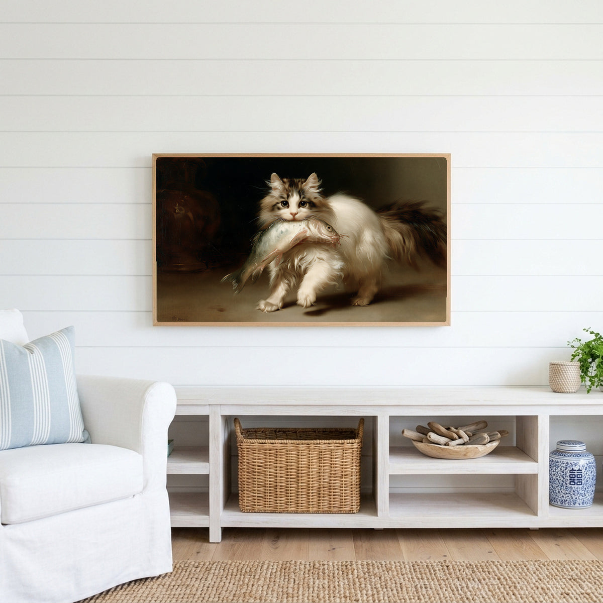 Kitten with a big fish Frame TV art above a white console with a rattan basket in a coastal living room