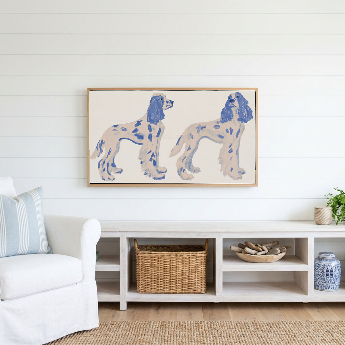 Spaniel figurines Frame TV art above a white console with a rattan basket in a coastal living room