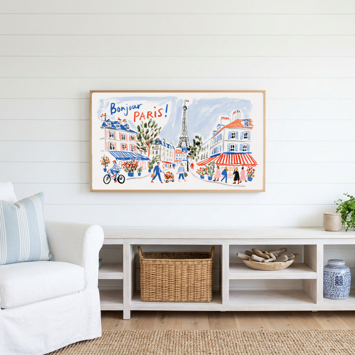 Bonjour Paris Frame TV art above a white console with a rattan basket in a coastal living room