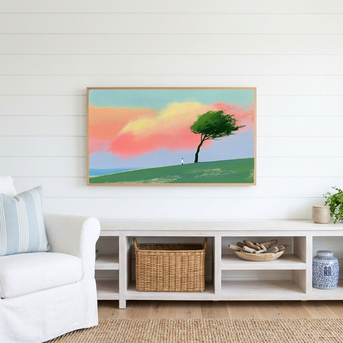 Tree on a hill at sunset Frame TV art above a white console with a rattan basket in a coastal living room
