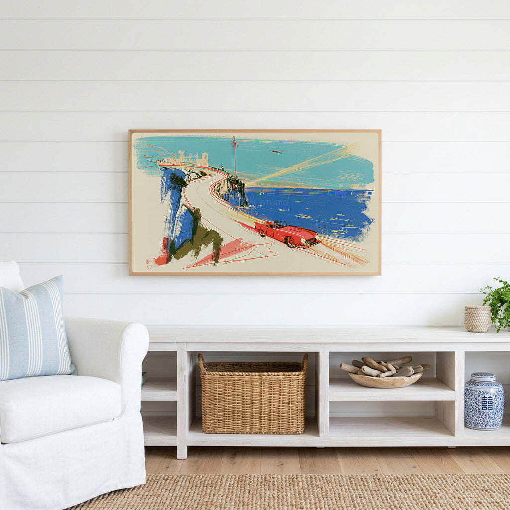 Red car on a coastal road Frame TV art above a white console with a rattan basket in a coastal living room