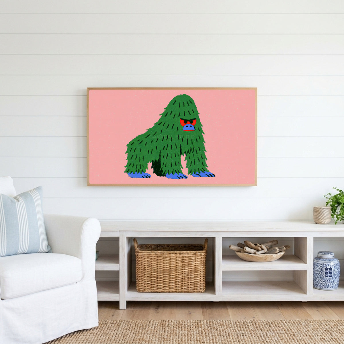 Grumpy gorilla Frame TV art above a white console with a rattan basket in a coastal living room