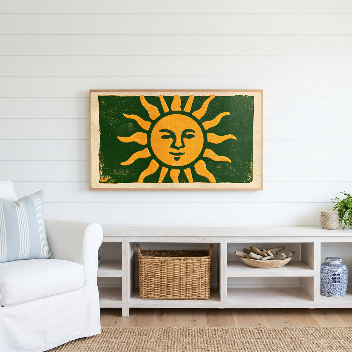 Woodblock sun Frame TV art above a white console with a rattan basket in a coastal living room