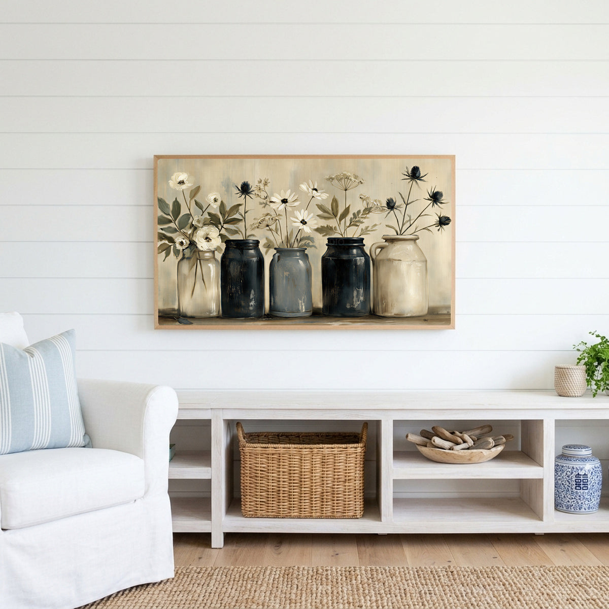 Farmhouse flower jars Frame TV art above a white console with a rattan basket in a coastal living room