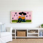 Woman in a big hat Frame TV art above a white console with a rattan basket in a coastal living room