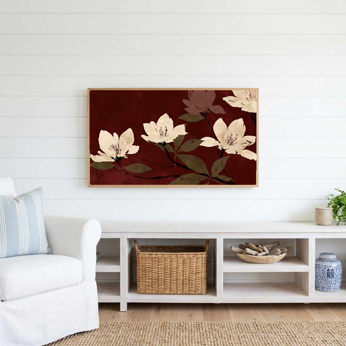 Cream blossoms on burgundy Frame TV art above a white console with a rattan basket in a coastal living room
