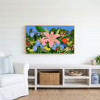 Tropical flower garden Frame TV art above a white console with a rattan basket in a coastal living room