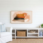 Book stack Frame TV art above a white console with a rattan basket in a coastal living room