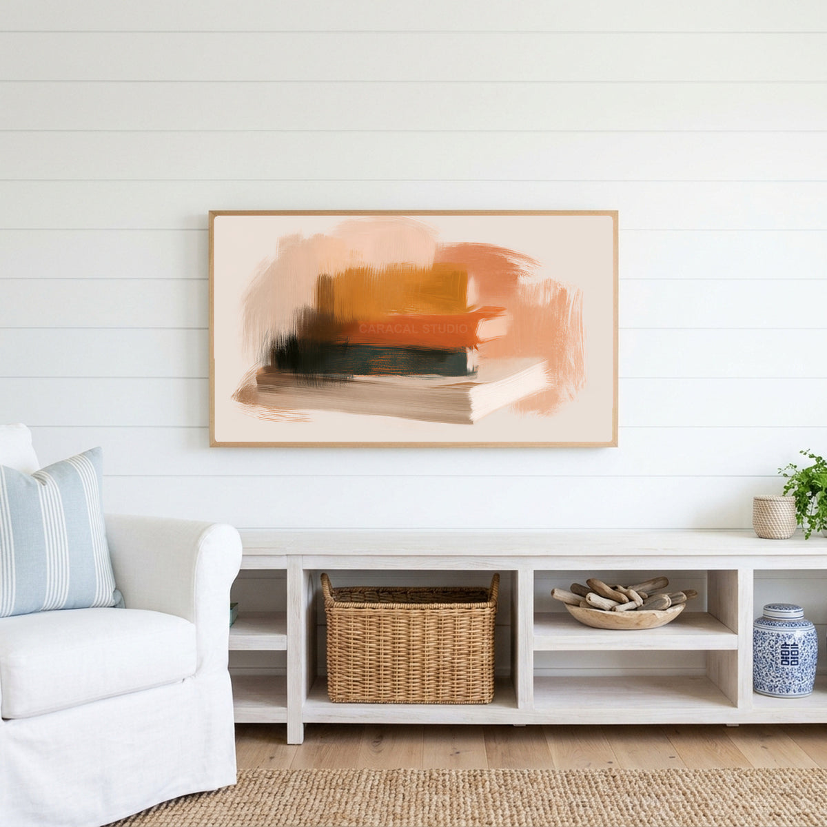 Book stack Frame TV art above a white console with a rattan basket in a coastal living room