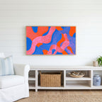 Wavy abstract shapes Frame TV art above a white console with a rattan basket in a coastal living room