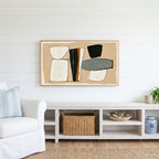 Mid century abstract shapes Frame TV art above a white console with a rattan basket in a coastal living room