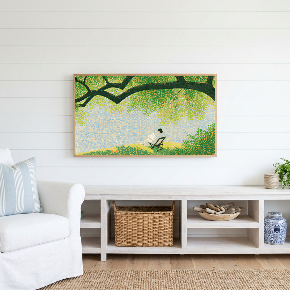 Lake and tree landscape Frame TV art above a white console with a rattan basket in a coastal living room