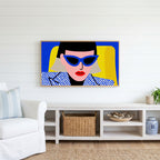 Pop art woman in sunglasses Frame TV art above a white console with a rattan basket in a coastal living room