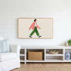 Woman walking Frame TV art above a white console with a rattan basket in a coastal living room