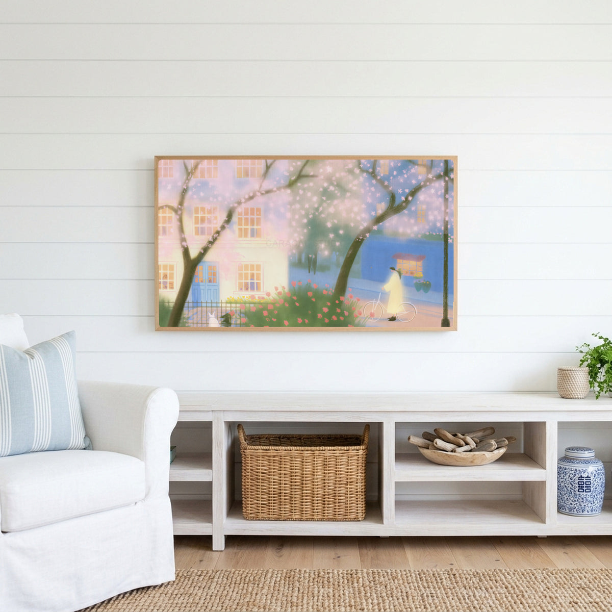 Cherry blossom street Frame TV art above a white console with a rattan basket in a coastal living room