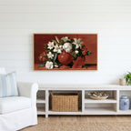 White lilies in a red vase Frame TV art above a white console with a rattan basket in a coastal living room