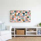 Pastel pebble mosaic Frame TV art above a white console with a rattan basket in a coastal living room