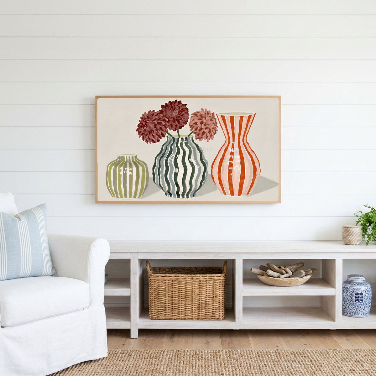 Striped vases Frame TV art above a white console with a rattan basket in a coastal living room