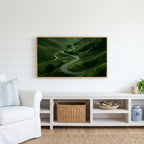 Winding road landscape Frame TV art above a white console with a rattan basket in a coastal living room