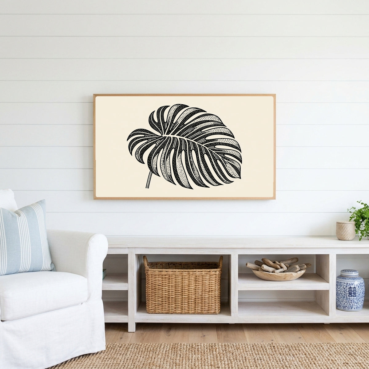 Monstera leaf Frame TV art above a white console with a rattan basket in a coastal living room