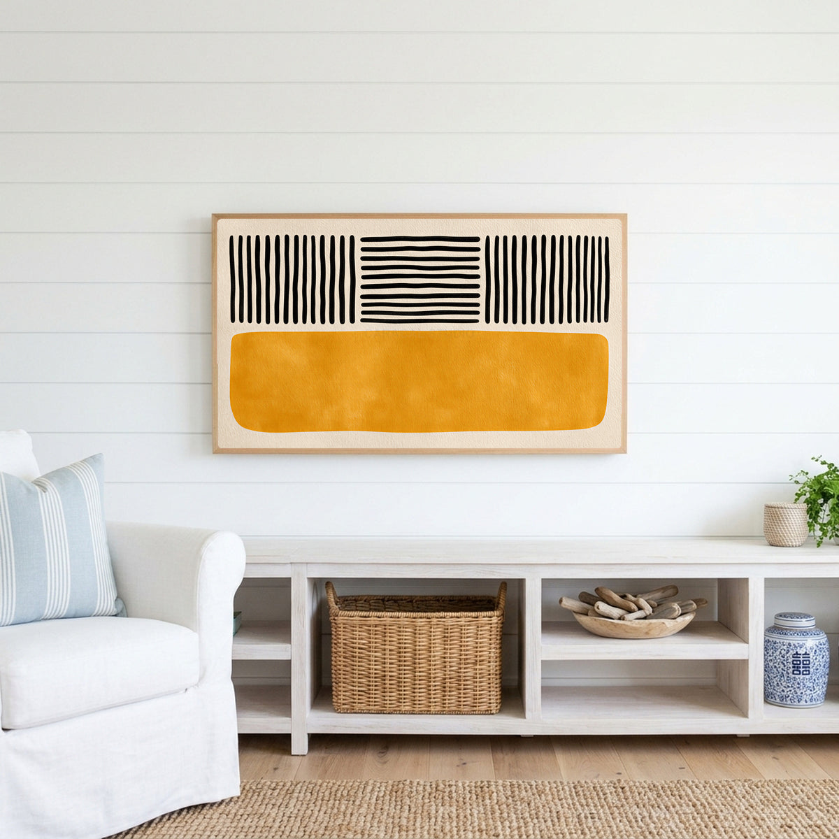 Abstract lines and color block Frame TV art above a white console with a rattan basket in a coastal living room