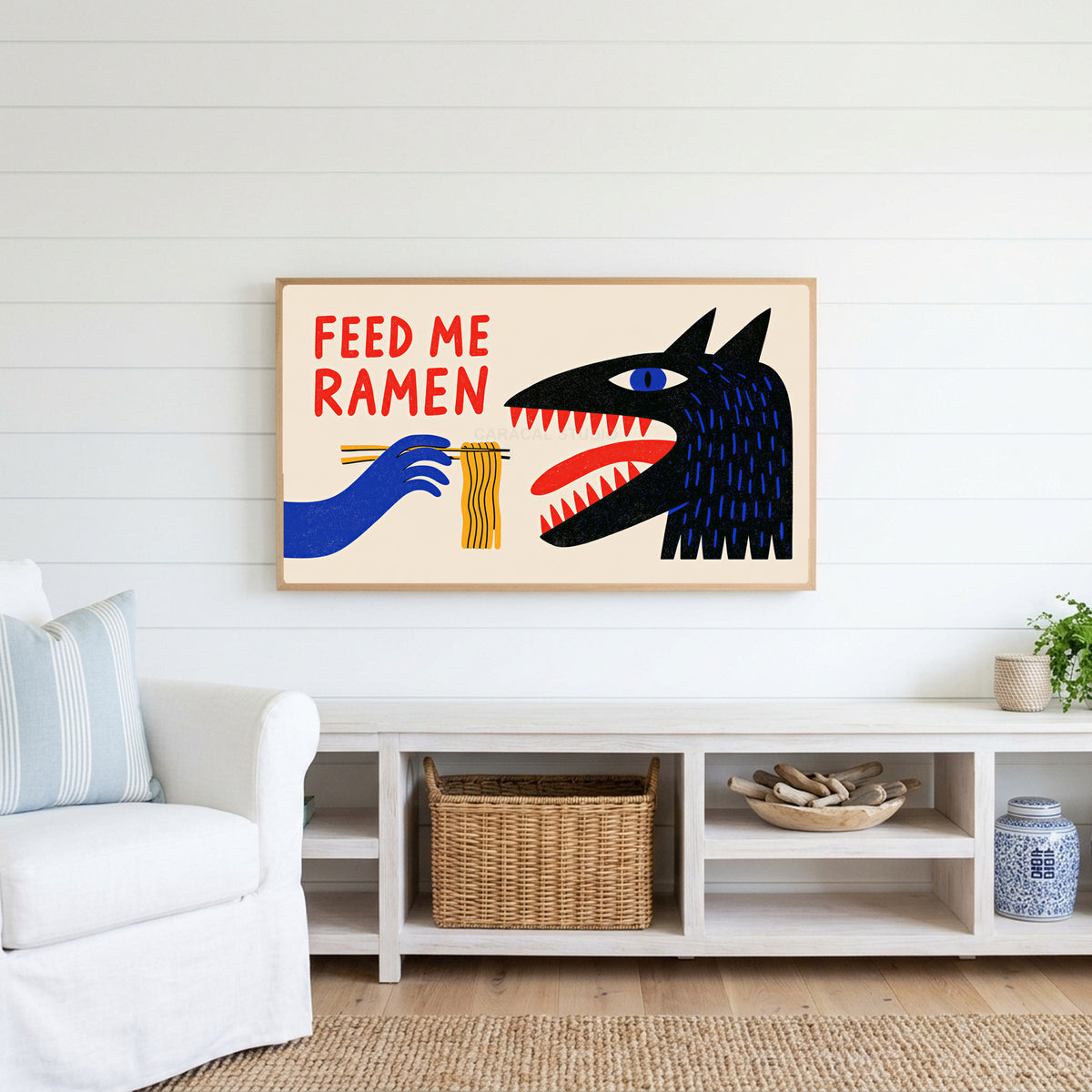 Feed Me Ramen Frame TV art above a white console with a rattan basket in a coastal living room