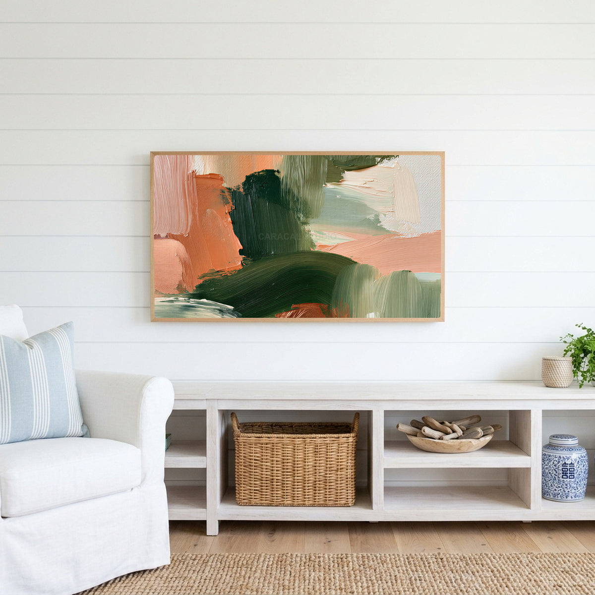 Green and peach abstract Frame TV art above a white console with a rattan basket in a coastal living room