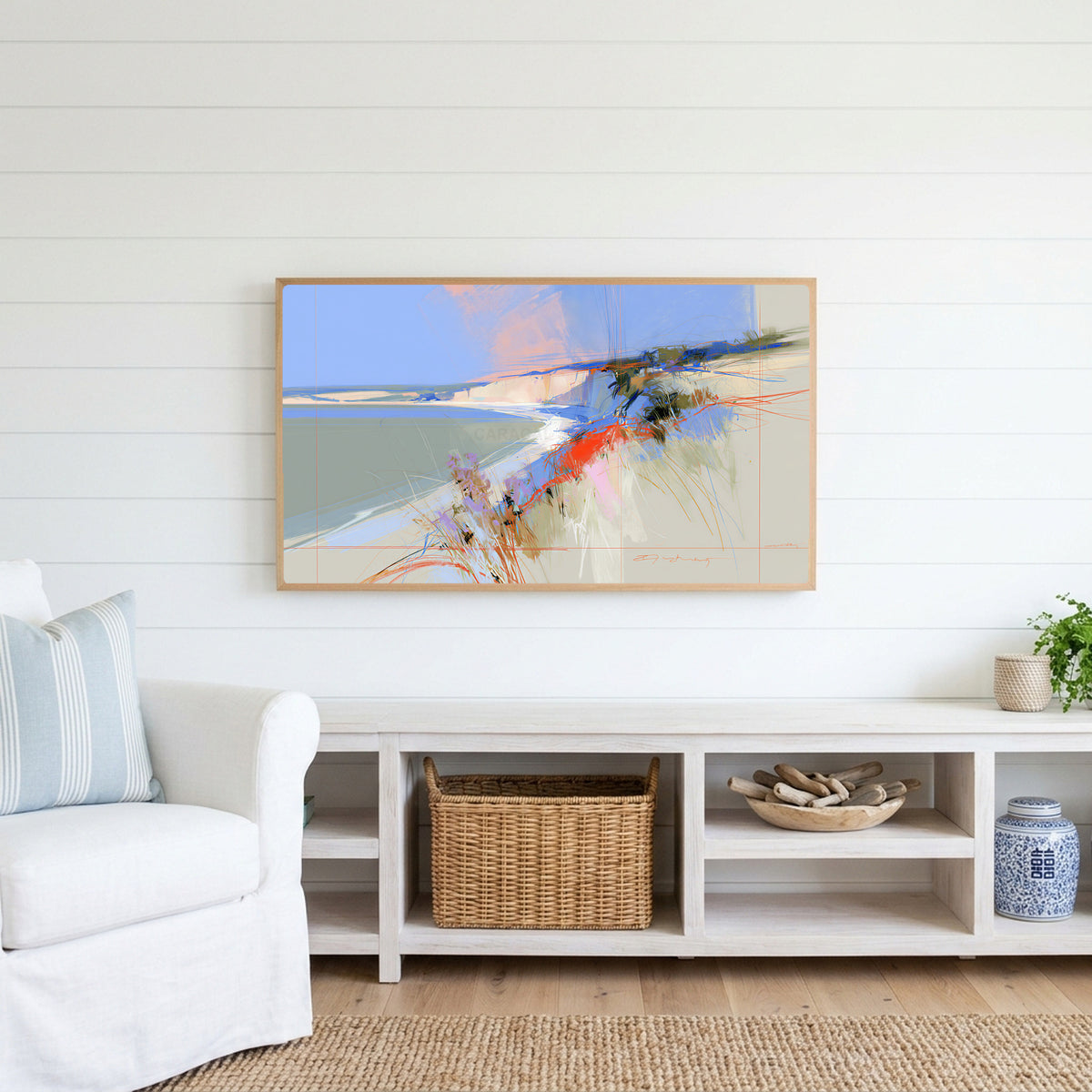 Abstract chalk cliffs Frame TV art above a white console with a rattan basket in a coastal living room