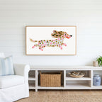 Running dachshund Frame TV art above a white console with a rattan basket in a coastal living room