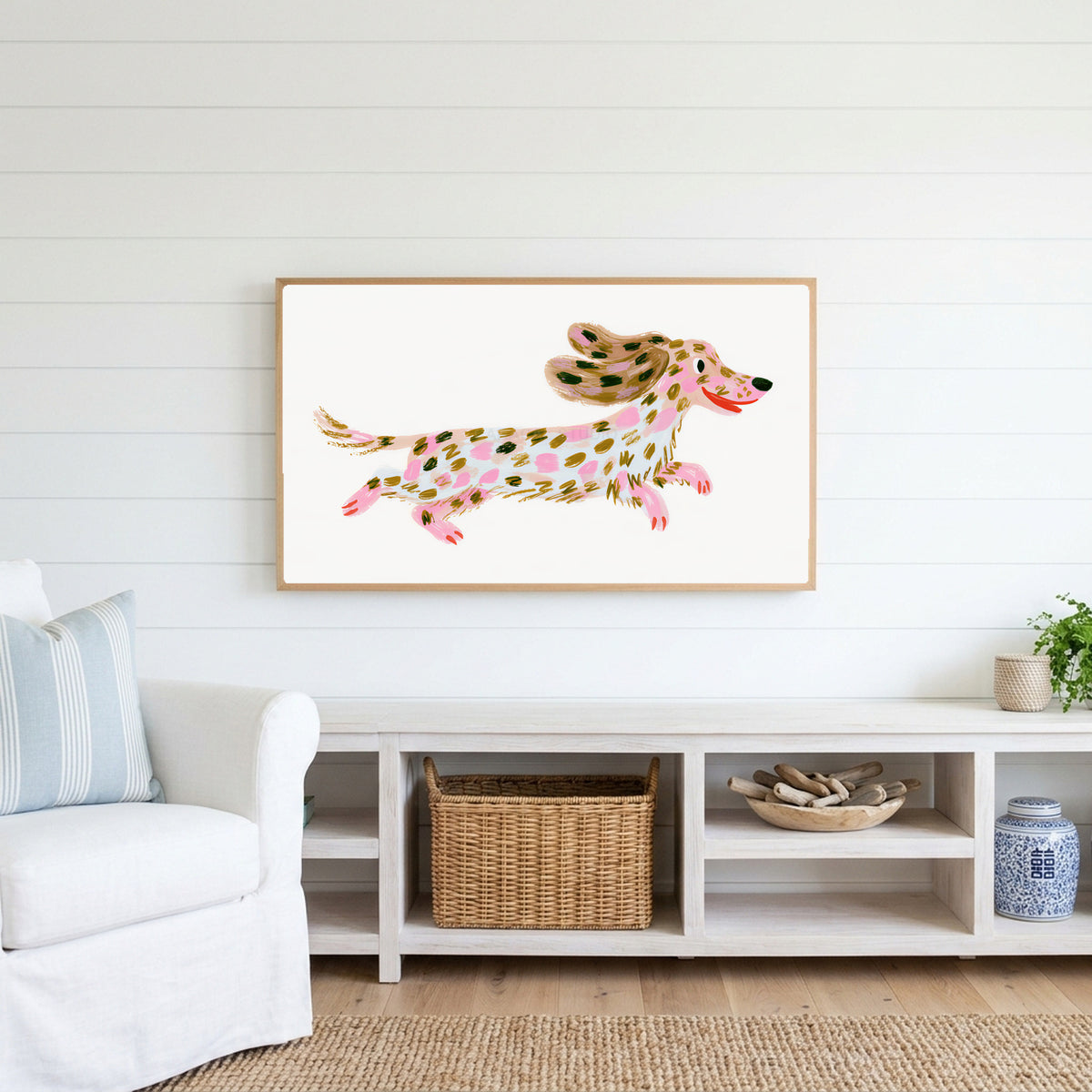Running dachshund Frame TV art above a white console with a rattan basket in a coastal living room