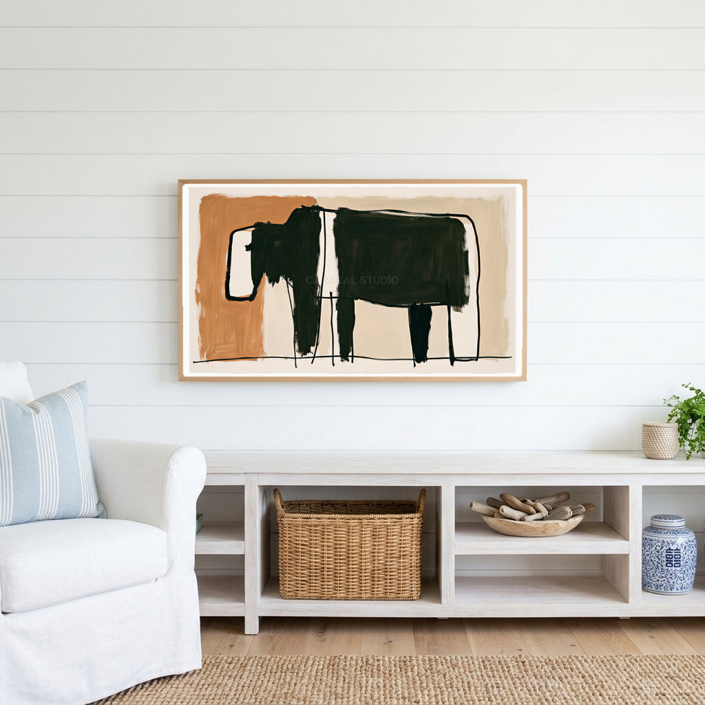 Minimalist black cow Frame TV art above a white console with a rattan basket in a coastal living room