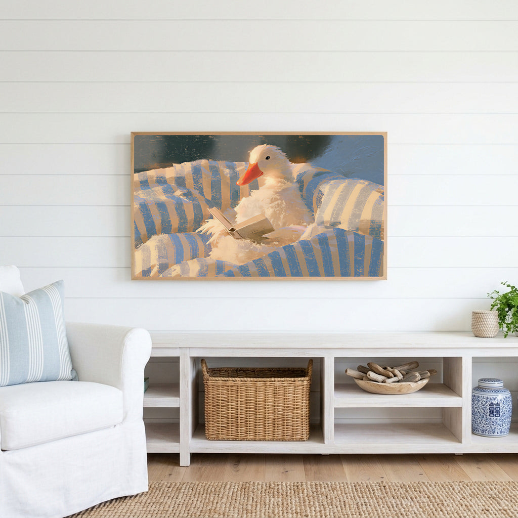 Duck reading in bed Frame TV art above a white console with a rattan basket in a coastal living room