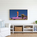 Pink car in the desert Frame TV art above a white console with a rattan basket in a coastal living room