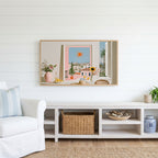 Athens summer still life Frame TV art above a white console with a rattan basket in a coastal living room