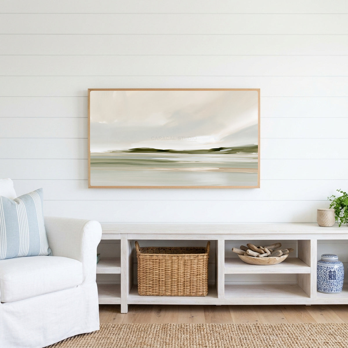 Misty sage shoreline Frame TV art above a white console with a rattan basket in a coastal living room