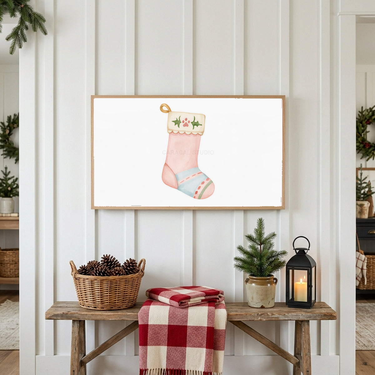 Cat stocking Frame TV art above a rustic bench with pine cones and a red check blanket on a white plank wall