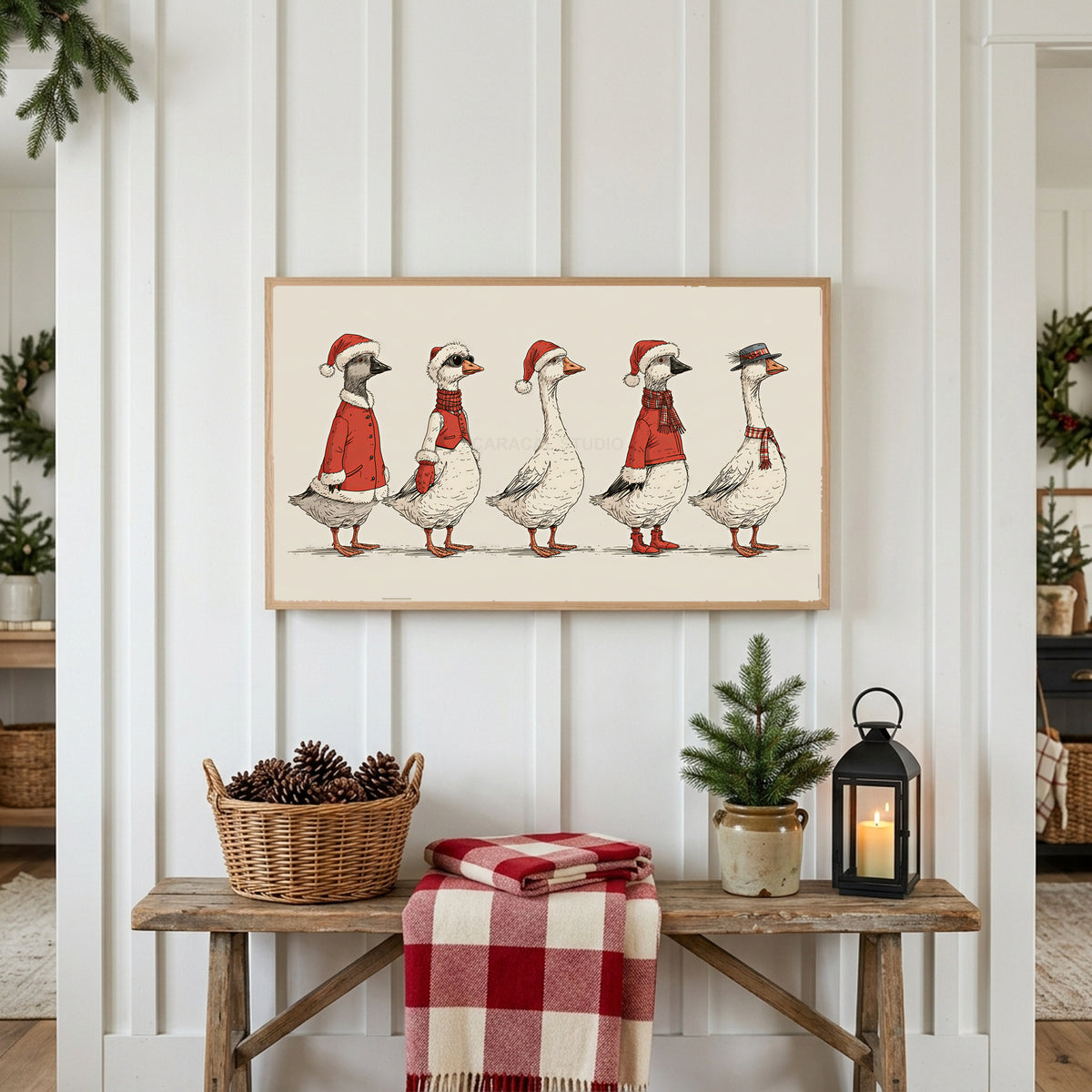 Geese in Santa hats Frame TV art above a rustic bench with pine cones and a red check blanket on a white plank wall