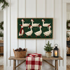 Geese in Santa hats Frame TV art above a rustic bench with pine cones and a red check blanket on a white plank wall