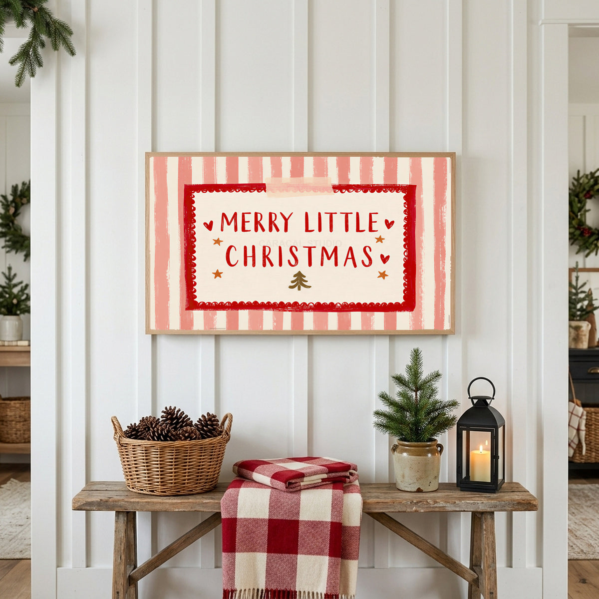 Merry Little Christmas Frame TV art above a rustic bench with pine cones and a red check blanket on a white plank wall