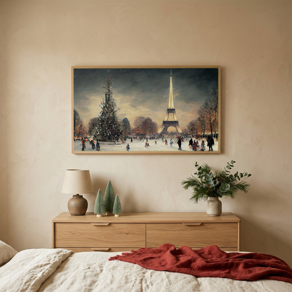Paris in snow Christmas TV art above an oak dresser with small bottle-brush trees in a calm bedroom
