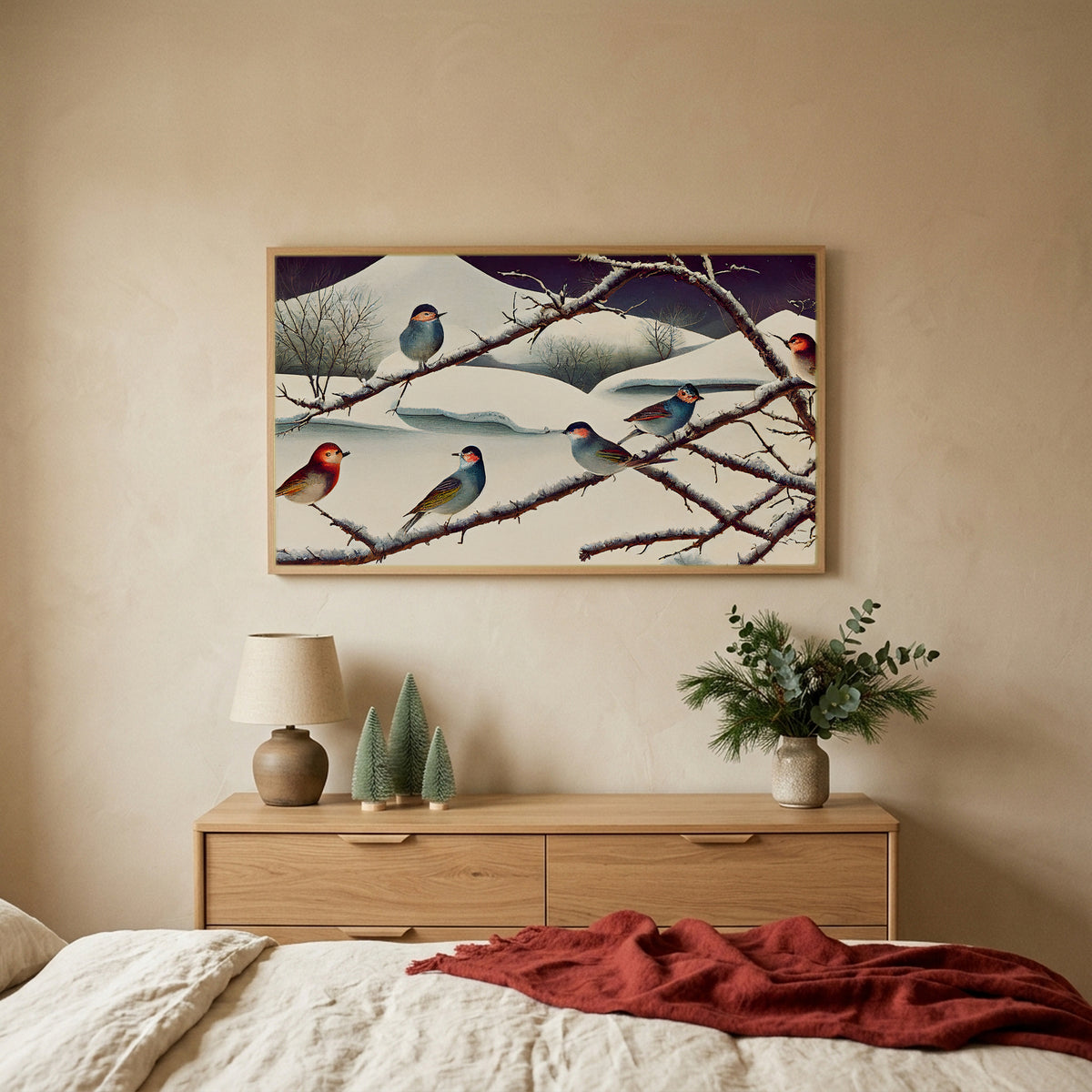 Songbirds on snowy branches TV art above an oak dresser with small bottle-brush trees in a calm bedroom