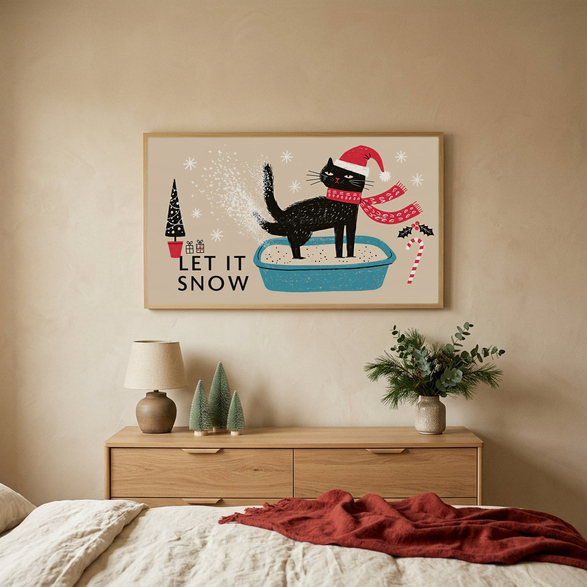 Let It Snow cat TV art above an oak dresser with small bottle-brush trees in a calm bedroom