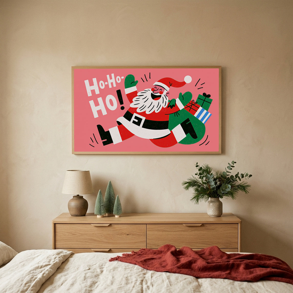 Jumping Santa TV art above an oak dresser with small bottle-brush trees in a calm bedroom