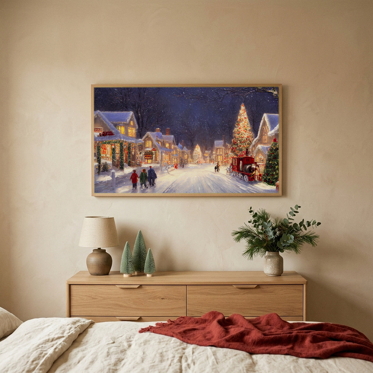 Snowy village with a red truck Christmas TV art above an oak dresser with small bottle-brush trees in a calm bedroom