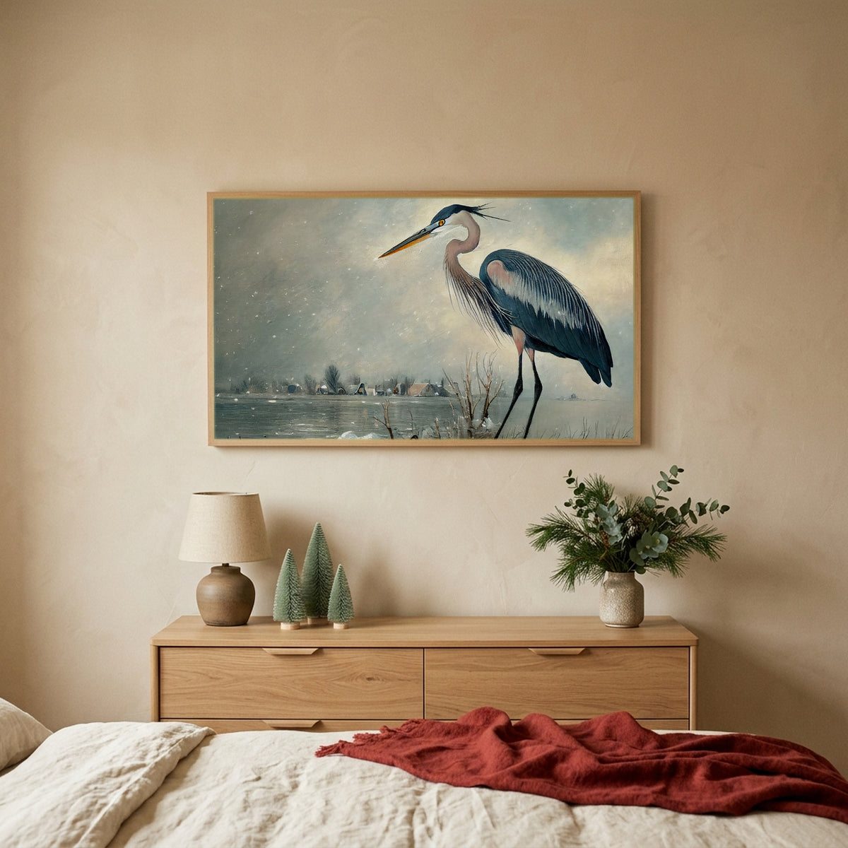 Blue heron TV art above an oak dresser with small bottle-brush trees in a calm bedroom
