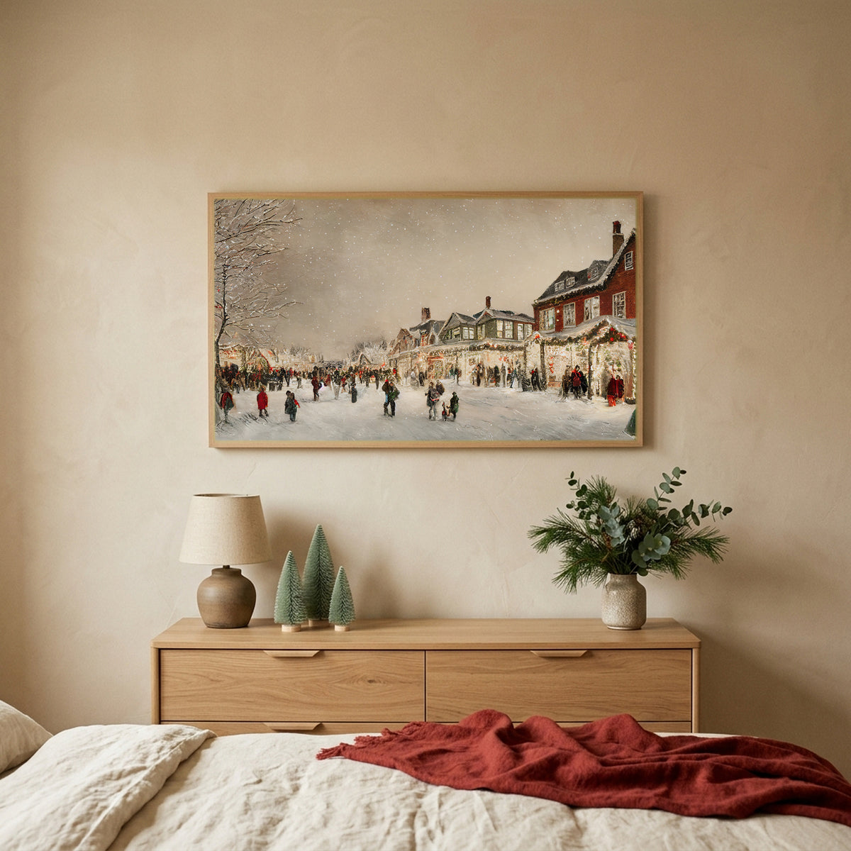 Christmas village street Christmas TV art above an oak dresser with small bottle-brush trees in a calm bedroom