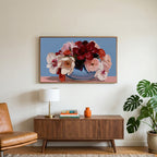 Peony and orchid bouquet art on a TV above a walnut credenza with a brass lamp and a monstera plant