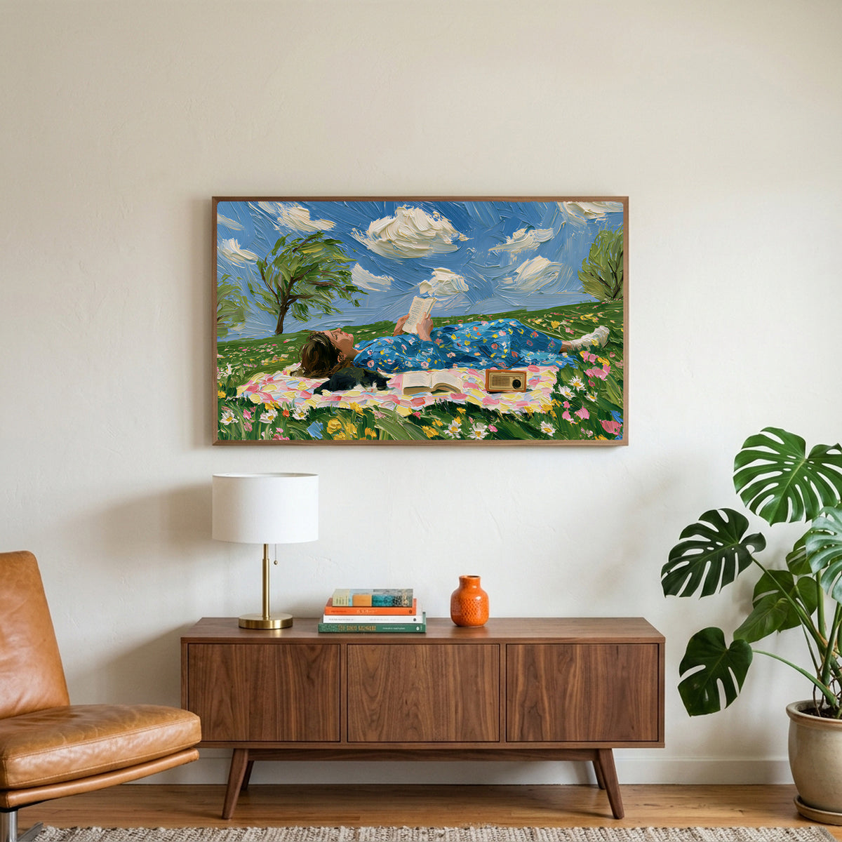 Picnic reader in a meadow art on a TV above a walnut credenza with a brass lamp and a monstera plant